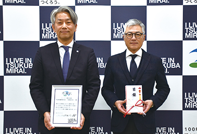 写真：（左）当社代表取締役社長八重島（右）つくばみらい市小田川市長